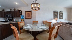 A dining area with a round table, chairs, and a chandelier.