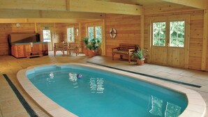 An indoor swimming pool with a wooden deck, seating area, and potted plants. - 2 bedroom accommodation in Near Ely (Near Ely)