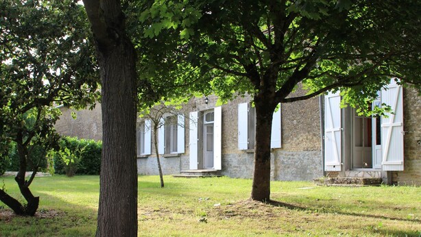 A courtyard with trees and a building with white shutters. - Logis near the chateau (Paizay-Naudouin-Embourie)