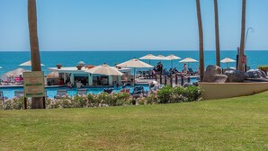 A resort pool area with umbrellas, lounge chairs, and a view of the ocean. - Sonoran Sea E-108 Sea-Gem Spectacular Spacious Oceanfront Condo (Puerto Peñasco)