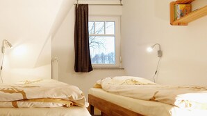 A room with two wooden beds, a window with a view of trees, and a bookshelf with books. - cozy apartment near the Darßwald, beach chair on balcony, WiFi, 4 pers. (Prerow)