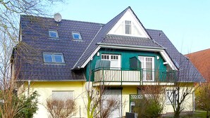 A two-story house with a green and yellow facade, a balcony, and a garage. - cozy apartment near the Darßwald, beach chair on balcony, WiFi, 4 pers. (Prerow)