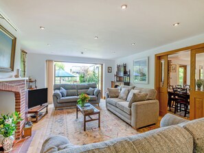 A spacious living room with a fireplace, sofas, a coffee table, and a television.
