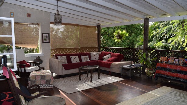 A cozy living room with a sofa, chairs, a coffee table, and a view of lush greenery outside. - Eco-friendly room in the Hummingbird apartment (St. Michael)