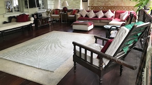 A spacious living room with a large wooden floor, a sofa set, a dining table, and a large rug. - Eco-friendly room in the Hummingbird apartment (St. Michael)