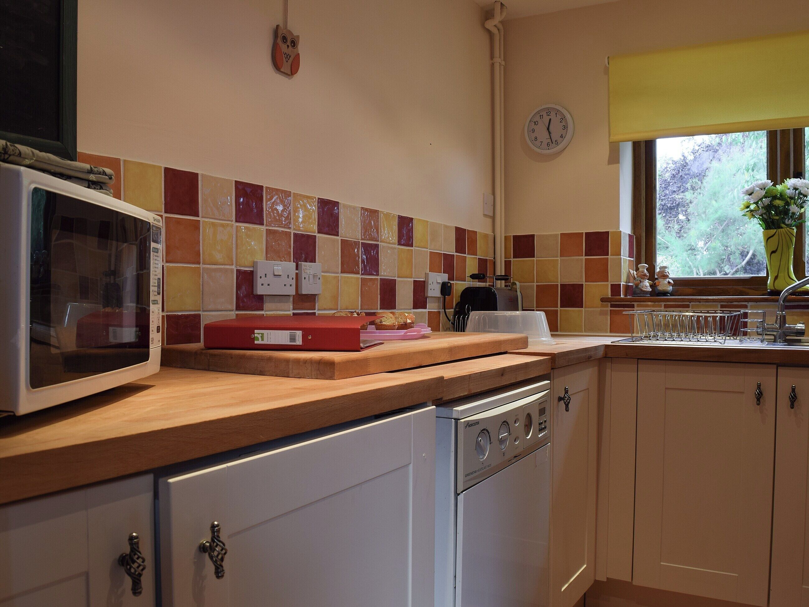 A kitchen with a microwave, toaster, and a clock on the wall.