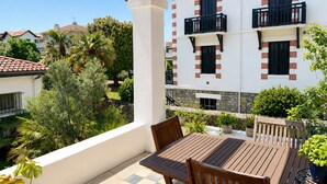 A balcony with a wooden table and chairs, surrounded by potted plants. - Architect-designed villa 200 m² 5 min from the beach (Saint-Jean-De-Luz)
