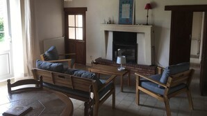 Una sala de estar acogedora con chimenea, muebles de madera y un cuadro enmarcado en la pared.