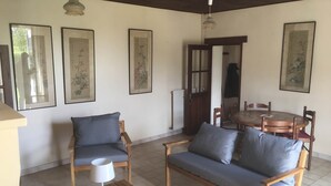 Una sala de estar acogedora con un sofá, sillas, una mesa y cuadros en las paredes.