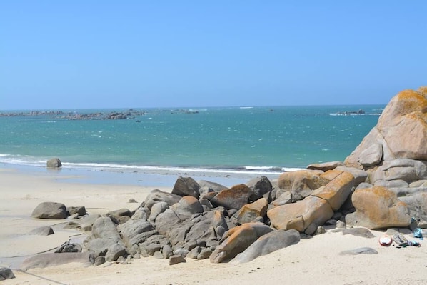 Ein felsiger Strand mit großen Felsen und freiem Blick auf das Meer.