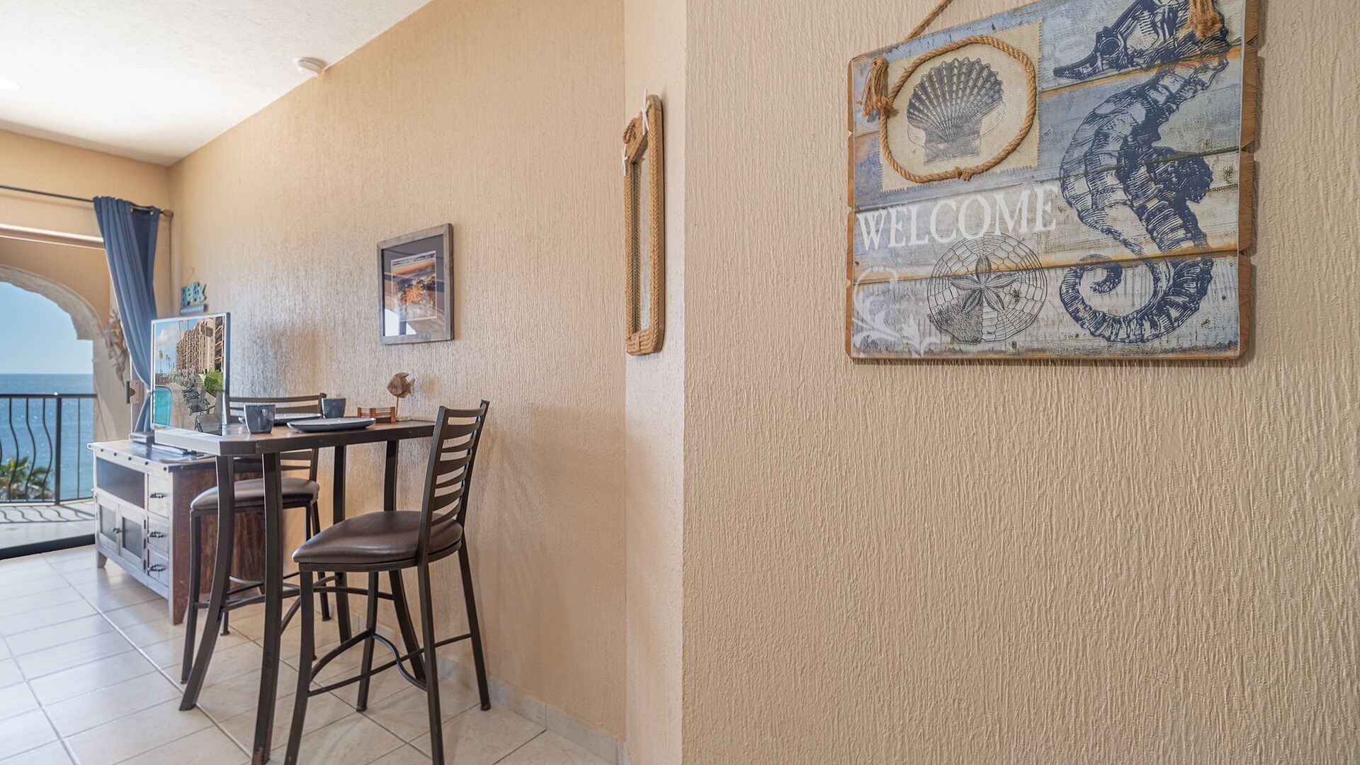 Un comedor con una mesa, sillas y un cartel que dice 'WELCOME' en la pared.