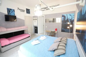 Ett sovrum med våningssängar, ett skrivbord, en stol, en platt-TV och en affisch med texten ”Fantasirum”.