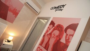 A hallway with a poster of a movie, a wall-mounted air conditioner, and a lamp. - Cineroma Guesthouse (Rome)