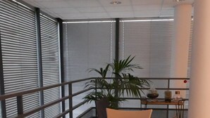 A dining area with a white table set for six, surrounded by chairs, with a plant on the table and a view of the city through large windows. - PARIS 12ème - 110 m² apartment near ARENA BERCY and Place DAUMESNIL (Paris)