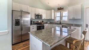 A modern kitchen with white cabinets, stainless steel appliances, and a granite countertop. - 4746- Sandy Feet Retreat - Oceanside Kitty Hawk Retreat w/ Pool (Kitty Hawk)