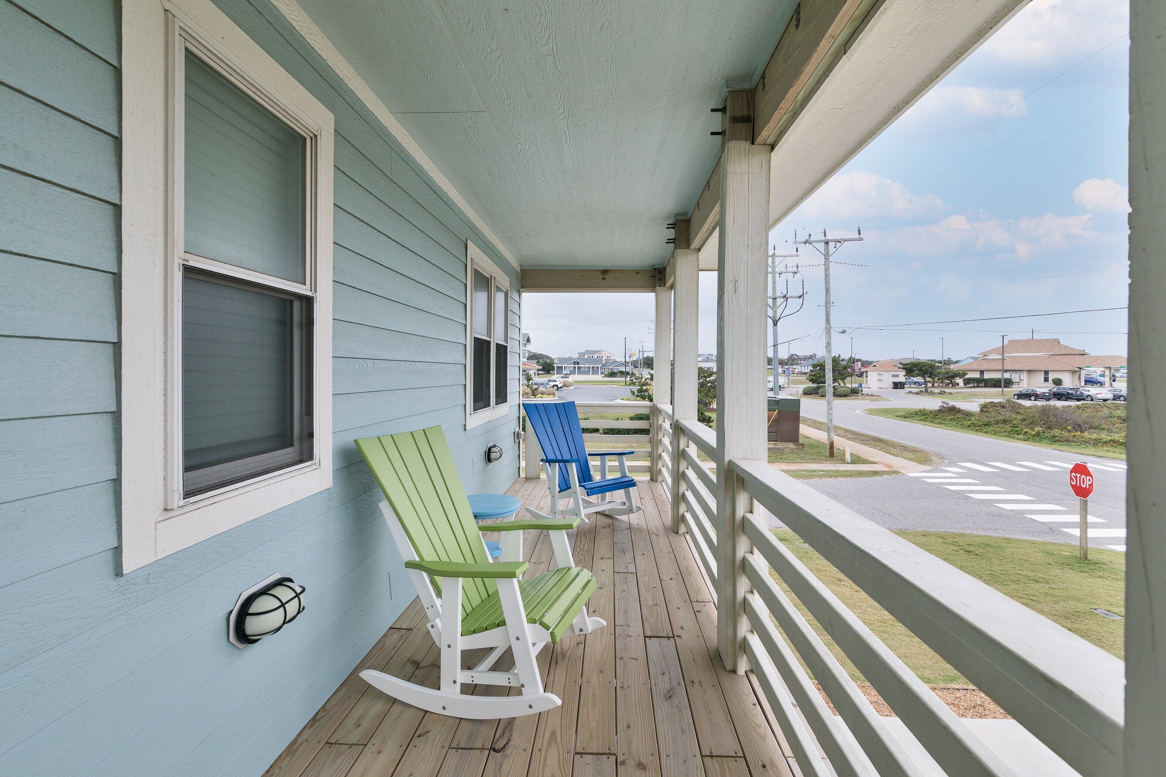A porch with rocking chairs and a stop sign visible in the background.