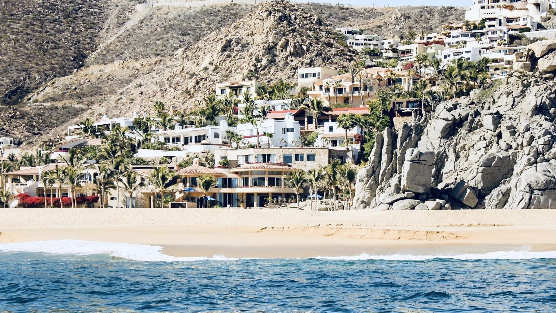 A coastal town with buildings built on a hillside overlooking the beach.