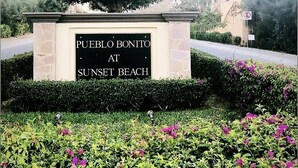 Placa de Pueblo Bonito na Praia do Pôr do Sol, com um jardim paisagístico em primeiro plano.