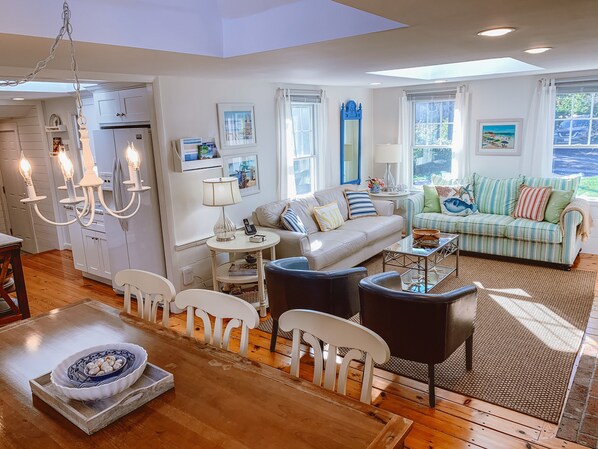 A spacious living room with a sofa, chairs, a coffee table, and a dining area with a table and chairs.