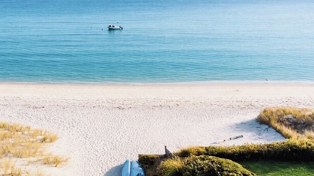 Een strand met een boot in het water en een heldere lucht.