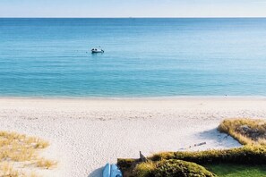 A beach with a boat in the water and a clear sky.