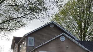 Een huis met twee verdiepingen, een houten terras en een stenen muur ervoor.