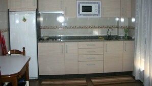 A compact kitchen with a refrigerator, microwave, sink, and wooden cabinets. - The Petra y Armando house in Anguiano (Anguiano)