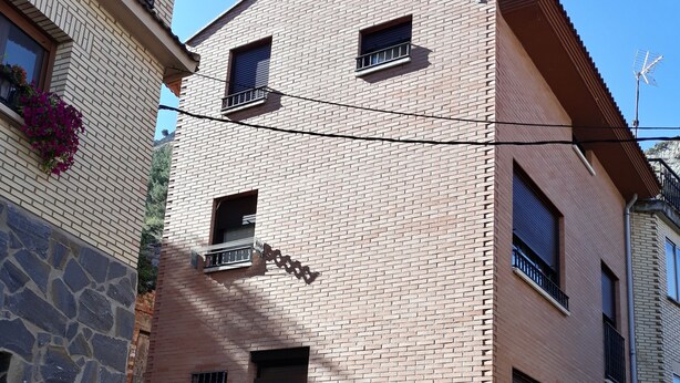 A two-story building with a brick facade, a black door, and multiple windows. - The Petra y Armando house in Anguiano (Anguiano)