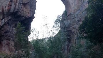 A stone bridge arching over a rocky gorge with a river below.