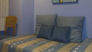 Un dormitorio con cama, almohadas, una silla y un cuadro en la pared.