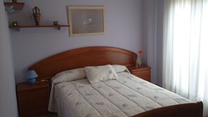 A bedroom with a wooden bed, a nightstand, a lamp, a vase with a flower, and a framed picture on the wall. - The Petra y Armando house in Anguiano (Anguiano)