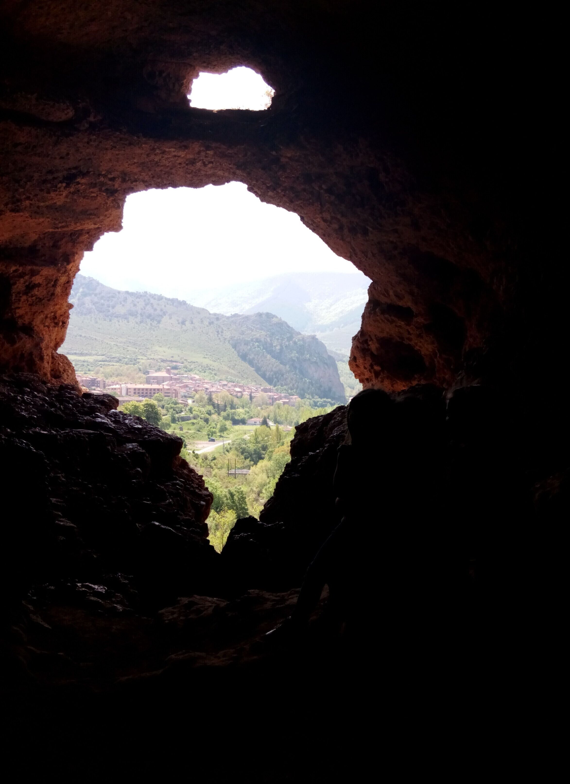 Eine Höhle mit Blick auf ein Tal und ferne Berge.