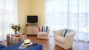 A living room with two sofas, a TV, and a small table with a vase of flowers.