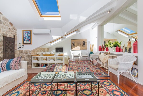 A spacious loft with high ceilings, skylights, and a mix of modern and traditional decor.