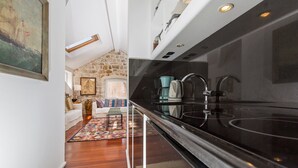 Una cocina moderna con encimera negra, electrodomésticos de acero inoxidable y pared de piedra.