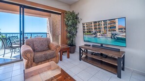 Ein Balkon mit einer Couch, einem Fernseher und einem Blumentopf.