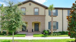 A two-story house with a front entrance, a small porch, and a well-maintained lawn. - 5BR Windsor Townhome | Private Splash Pool | Sleeps 12 | Dog Friendly | Near Disney (kissimmee)
