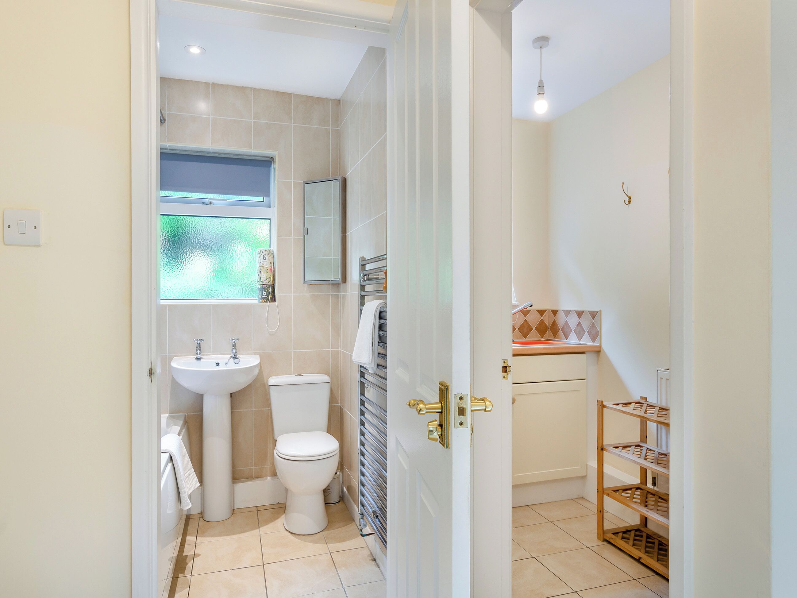 A bathroom with a toilet, sink, and a window.