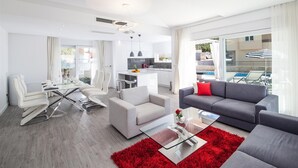 Un salon moderne avec un canapé gris, des chaises blanches et un tapis rouge.
