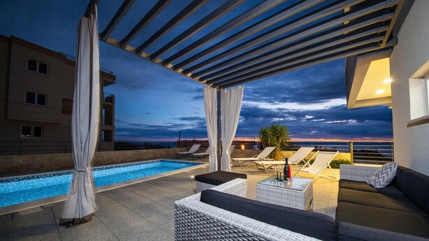Un espace piscine aménagé sur le toit, avec des chaises longues et une pergola.