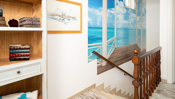 Un escalier avec une rampe en bois et une vue sur l’océan par une fenêtre.