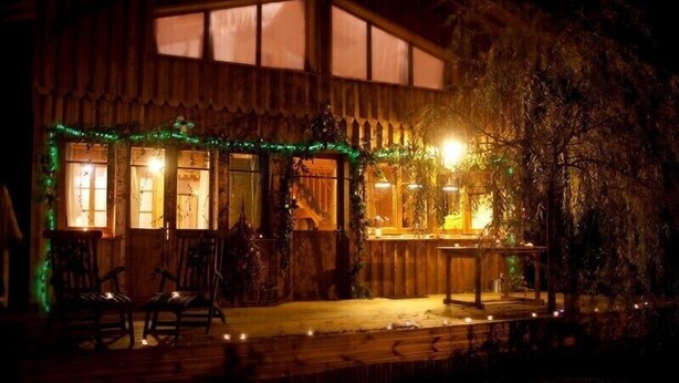 Ein hölzernes Gebäude mit Veranda, verziert mit Lichterketten und Pflanzen.