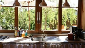 Eine Küche mit Spüle, Holzschränken und einem Fenster mit Blick ins Grüne.