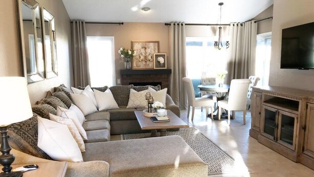 A modern living room with a sectional sofa, ottoman, and a dining area with a table and chairs. - Mountain Home Stallion Springs Ca. Luxury accommodation with Incredible views.  (Tehachapi)