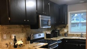 A kitchen with dark cabinets, a stainless steel oven, a granite countertop, and a window with blinds. - Mountain Home Stallion Springs Ca. Luxury accommodation with Incredible views.  (Tehachapi)