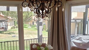 A dining area with a chandelier, round table, chairs, and a vase with flowers. - Mountain Home Stallion Springs Ca. Luxury accommodation with Incredible views.  (Tehachapi)