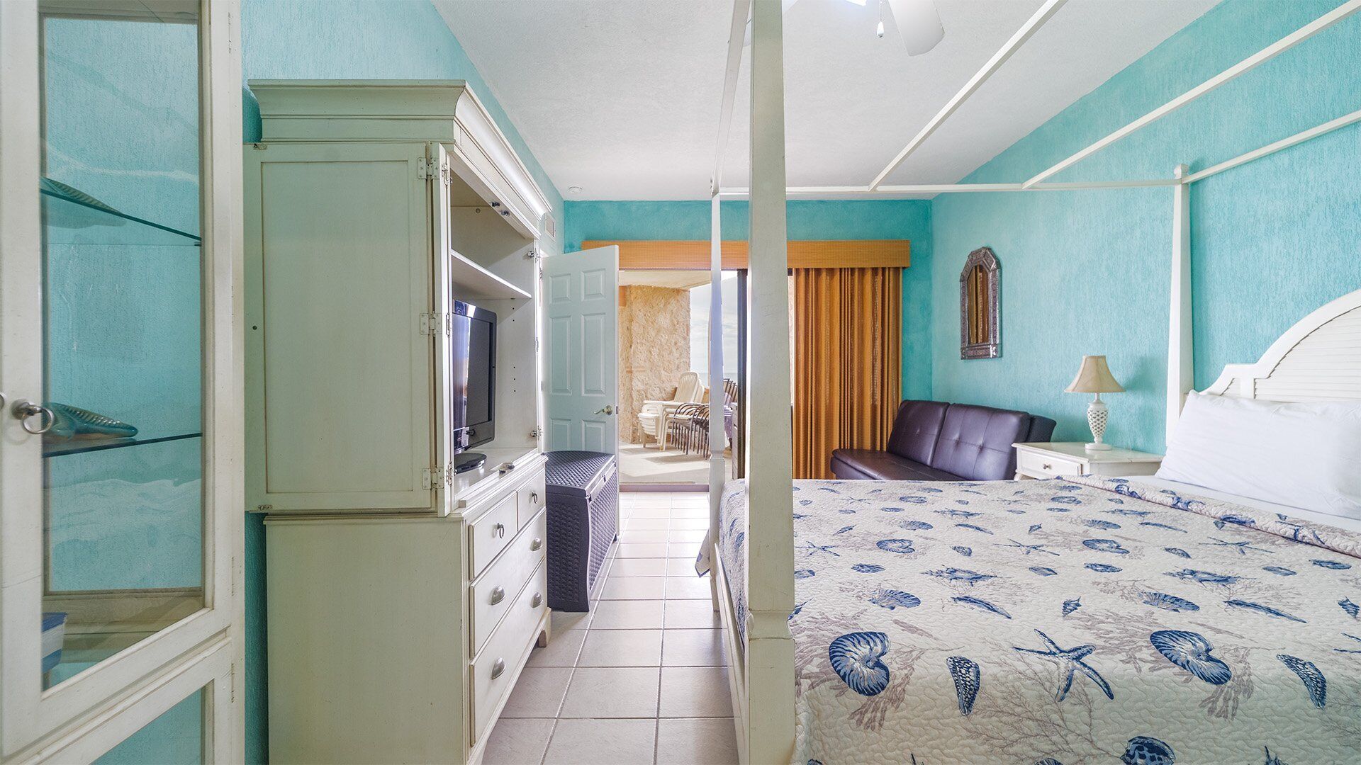 Une chambre d’hôtel comprenant un lit, une télévision, une armoire, une salle de bain et un balcon avec des chaises.