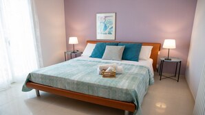 Ein ordentlich bezogenes Bett mit einer blauen und weißen Tagesdecke, zwei Nachttische mit Lampen und ein gerahmtes Bild an der Wand.