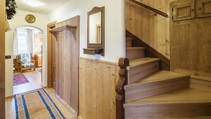 A wooden staircase with a handrail, a mirror on the wall, and a door with a coat rack.