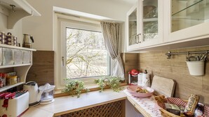 A kitchen with a window, a toaster, a kettle, and a basket of bread.
